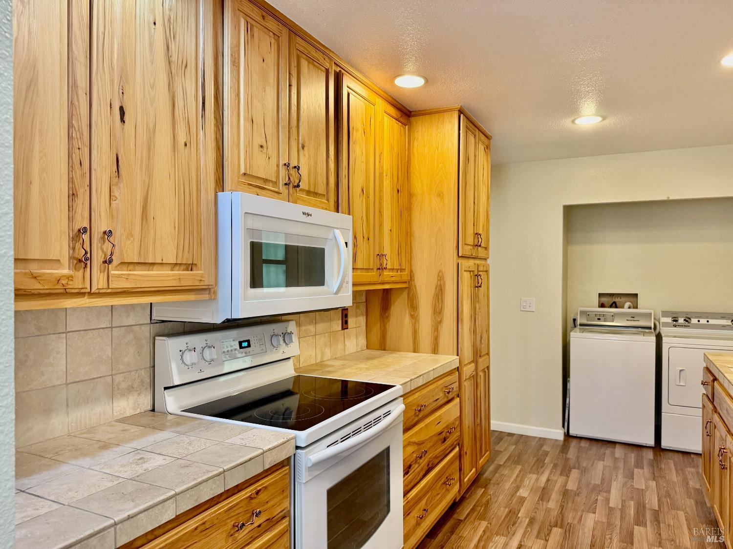 1945 Piner Road, Unit 16 Santa Rosa, CA 95403 - Photo 9 of 21 a kitchen with stainless steel appliances granite countertop a stove a sink and a refrigerator with wooden floor