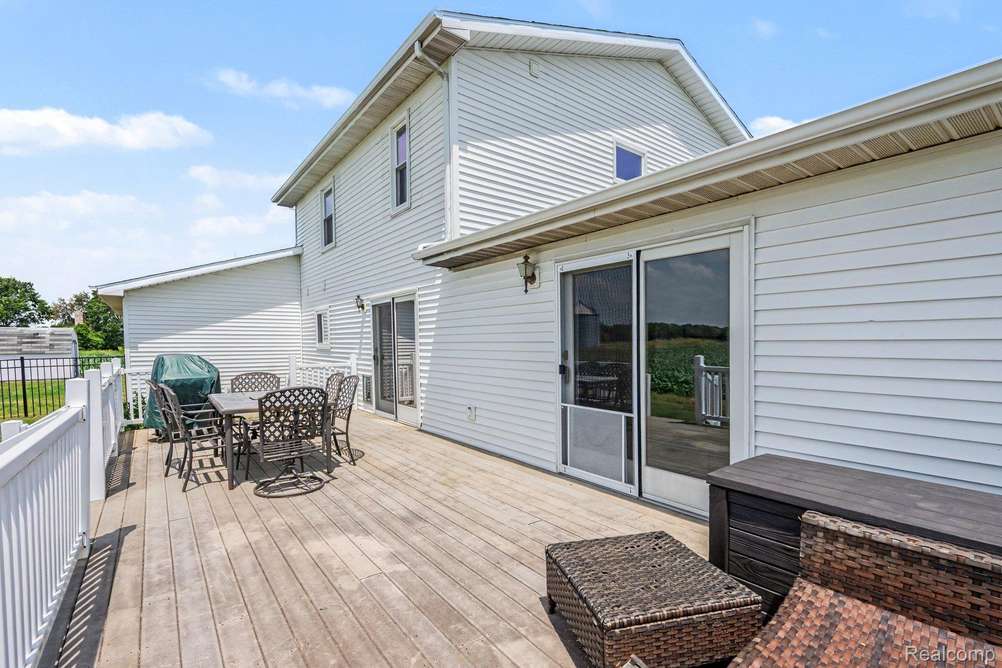 996 Arbogast Road Union City, MI 49094 - Photo 23 of 34 Expansive wood deck with white railing, featuring white siding exterior, sliding glass doors, and a partial black metal fence