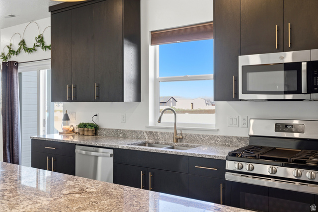 3902 West 825 North West Point, UT 84015 - Photo 23 of 49 Kitchen featuring stainless steel appliances, light stone counters, and dark wood finish cabinetry