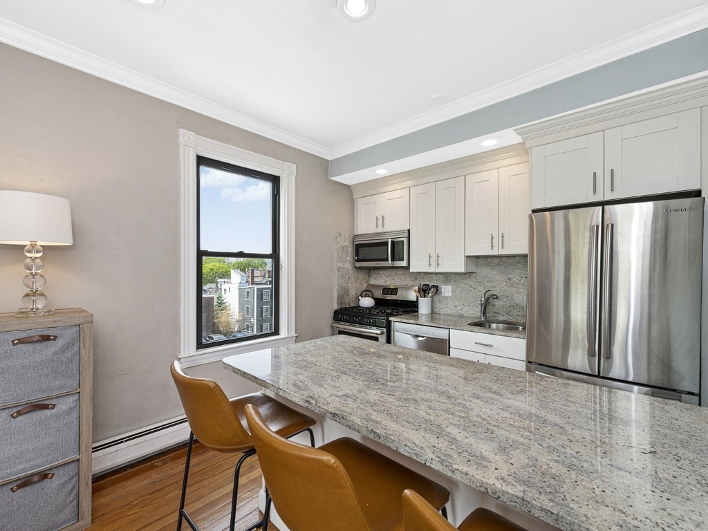 58 Winthrop Street, Unit 3 Boston, MA 02129 - Photo 5 of 14 a kitchen with stainless steel appliances granite countertop a stove a refrigerator a sink a dining table and chairs with wooden floor
