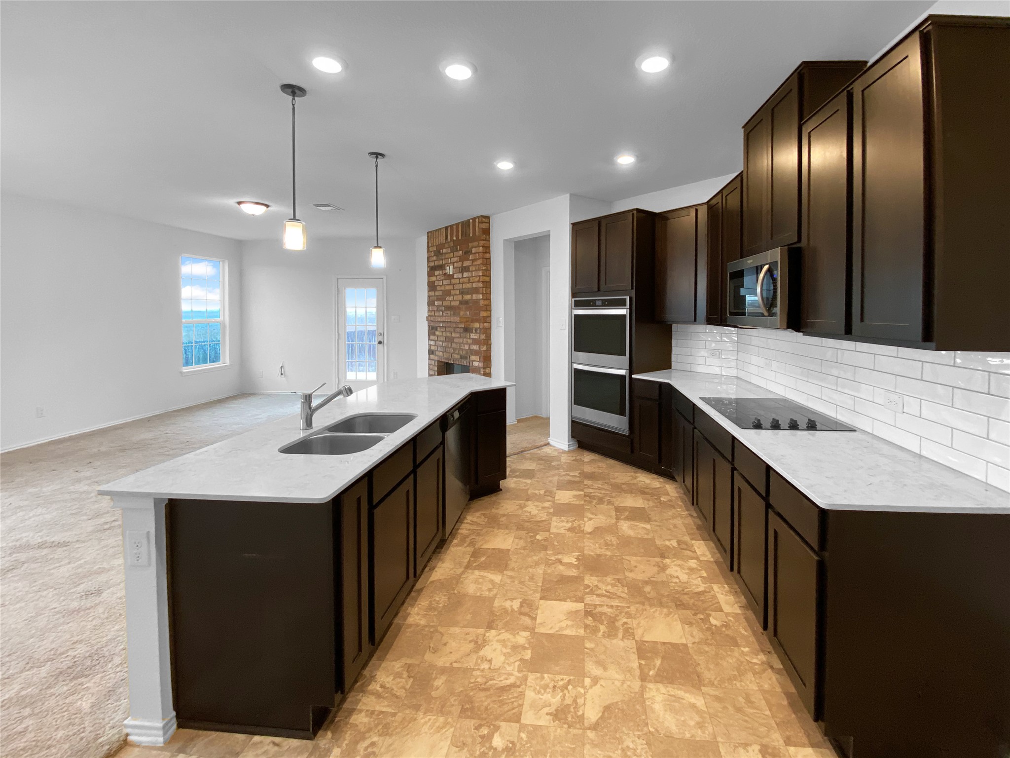 932 Yellow Ribbon Trail Jarrell, TX 76537 - Photo 23 of 26 Kitchen with dark wood finish cabinetry, light stone countertops, open floor plan, stainless steel appliances, and stone finish flooring