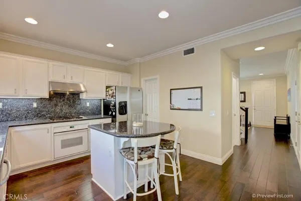 a kitchen with stainless steel appliances a dining table chairs and wooden floor