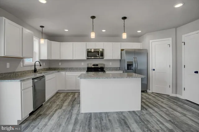 a kitchen with kitchen island a sink stainless steel appliances and cabinets
