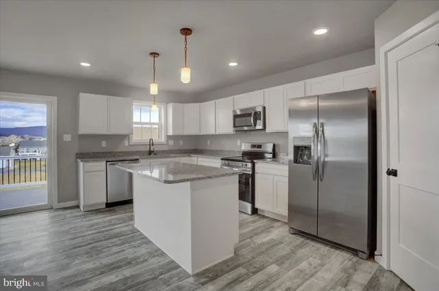 an empty room with kitchen view and wooden floor