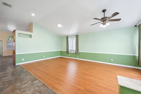 a view of a room with window a ceiling fan and wooden floor