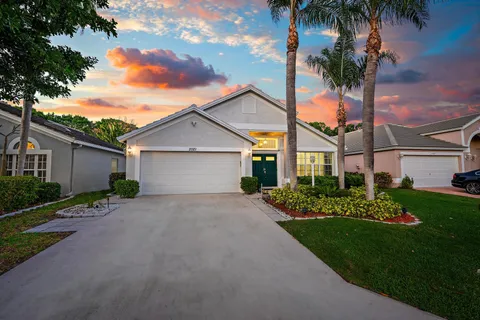 front view of a house with a yard and palm trees