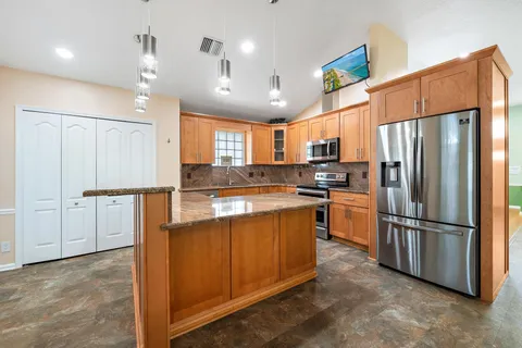 a kitchen with stainless steel appliances granite countertop a refrigerator a sink dishwasher a stove and a refrigerator with wooden floor
