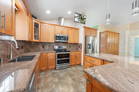 a large kitchen with stainless steel appliances granite countertop a stove a sink and a microwave