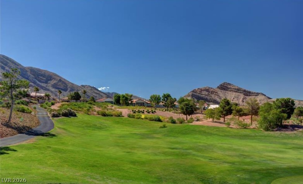 2716 Showcase Drive Las Vegas, NV 89134 - Photo 39 of 45 A vibrant green golf course is nestled against a striking mountain range, featuring residential properties on the hillside.