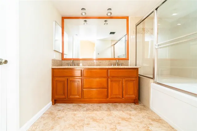 a bathroom with a granite countertop sink mirror shower and a bathtub