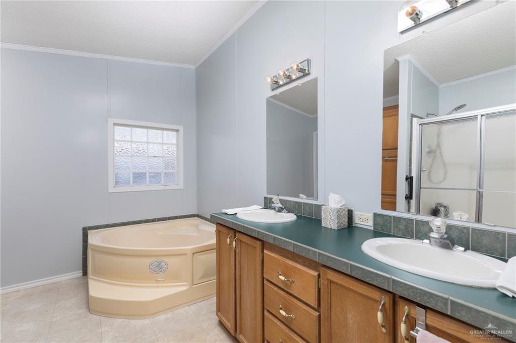 1034 Santa Maria Street Mercedes, TX 78570 - Photo 16 of 25 a bathroom with a granite countertop sink a mirror and a bathtub