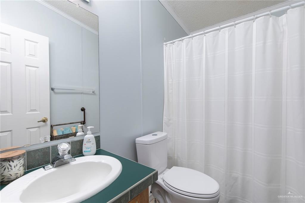 1034 Santa Maria Street Mercedes, TX 78570 - Photo 20 of 25 a bathroom with a sink a toilet a mirror and shower curtain
