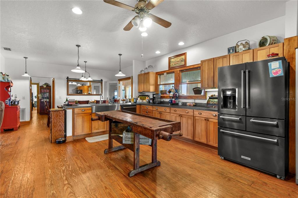 10807 Northwest Lily County Line Road Ona, FL 33865 - Photo 47 of 91 a kitchen with stainless steel appliances kitchen island granite countertop a refrigerator a stove a sink dishwasher and a dining table with wooden floor