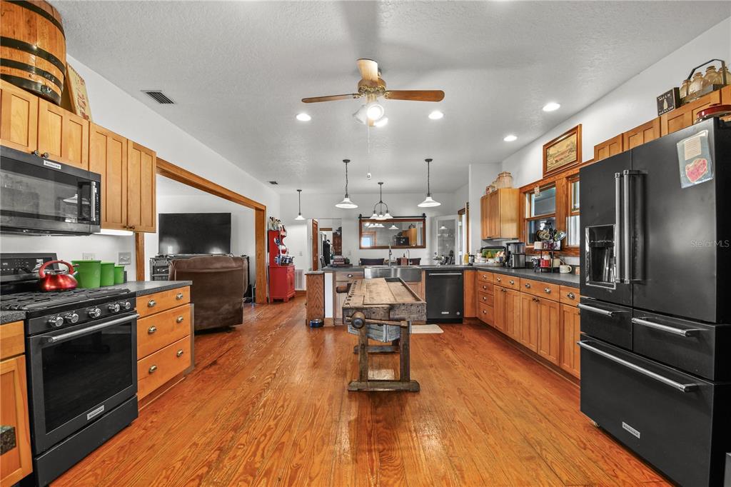10807 Northwest Lily County Line Road Ona, FL 33865 - Photo 49 of 91 a kitchen with stainless steel appliances kitchen island granite countertop a refrigerator a stove top oven a sink dishwasher and white cabinets with wooden floor