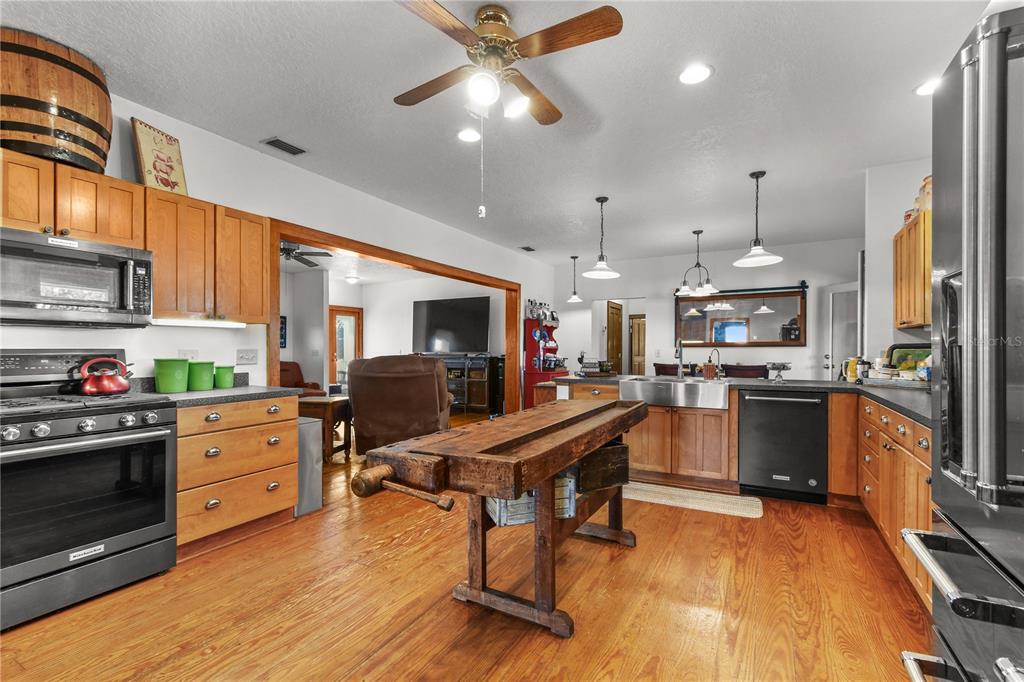 10807 Northwest Lily County Line Road Ona, FL 33865 - Photo 50 of 91 a kitchen with stainless steel appliances kitchen island granite countertop a refrigerator a stove top oven a sink dishwasher and white cabinets with wooden floor