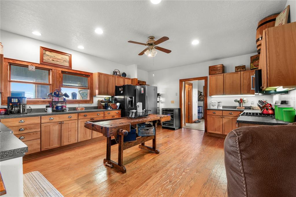 10807 Northwest Lily County Line Road Ona, FL 33865 - Photo 52 of 91 a kitchen with stainless steel appliances kitchen island granite countertop a refrigerator a stove top oven a sink dishwasher and white cabinets with wooden floor