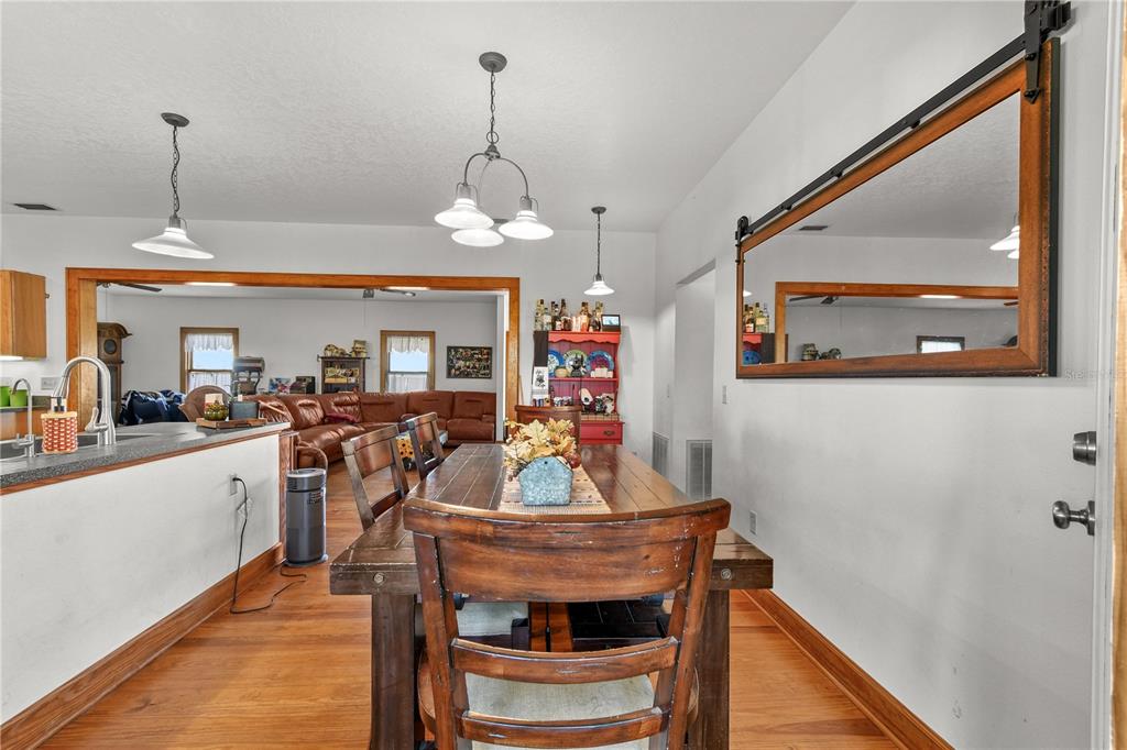 10807 Northwest Lily County Line Road Ona, FL 33865 - Photo 57 of 91 a view of a dining room and livingroom with furniture wooden floor a chandelier
