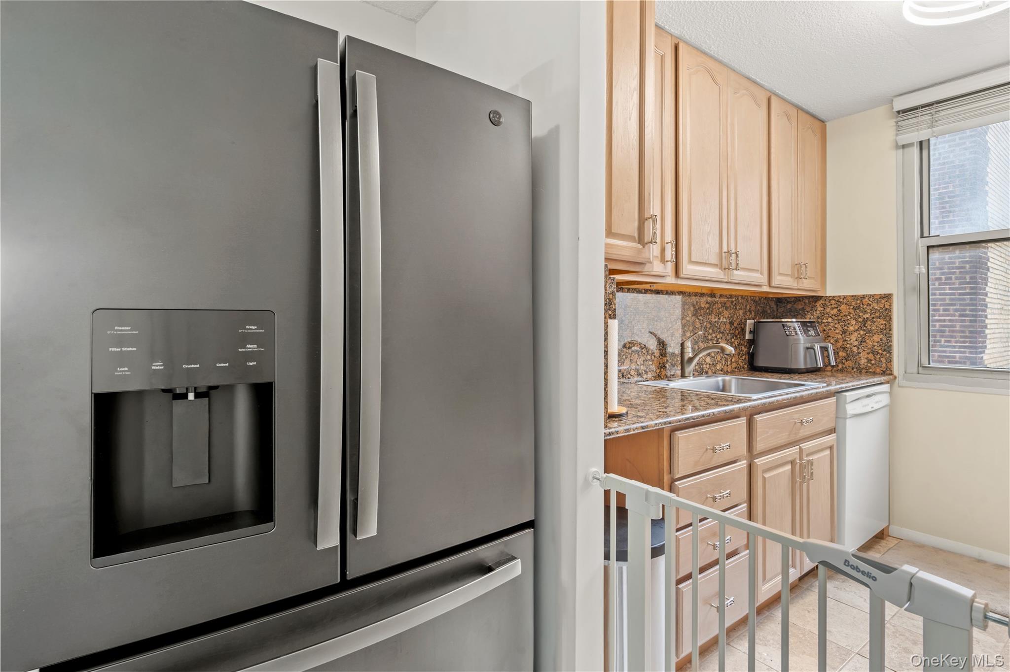 118-18 Union Turnpike, Unit 5F Queens, NY 11415 - Photo 5 of 13 Kitchen featuring stainless steel fridge, light brown cabinetry, dark stone countertops, and tasteful backsplash