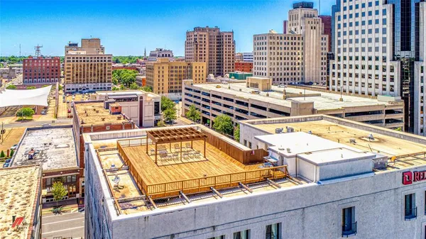 a view of a roof deck with table and chairs a barbeque with wooden floor and fence