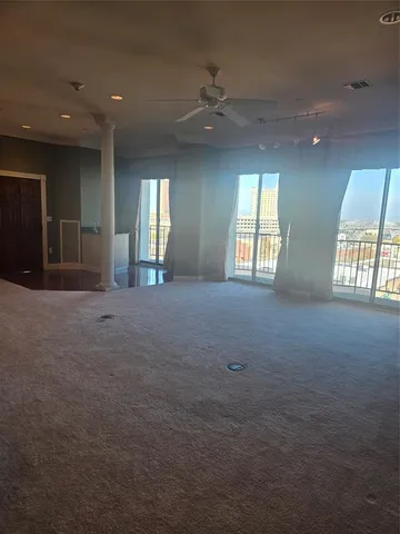 an empty room with windows and ceiling fan