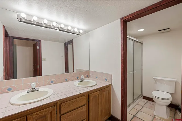 a bathroom with a granite countertop sink a toilet and a mirror