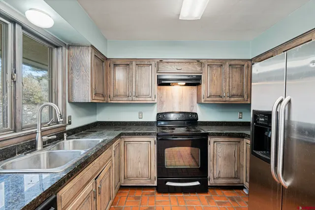 a kitchen with kitchen island granite countertop a sink stove and refrigerator