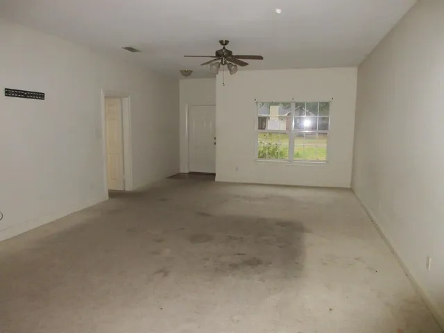 an empty room with a ceiling fan and window