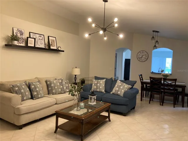 a living room with furniture kitchen view and a chandelier
