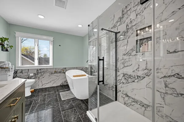 a bed sitting in a spacious bedroom next to a window