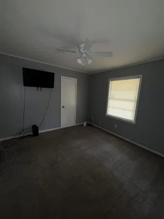 an empty room with windows and fan