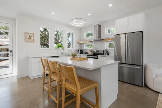 a kitchen with stainless steel appliances a refrigerator a stove a dining table and chairs