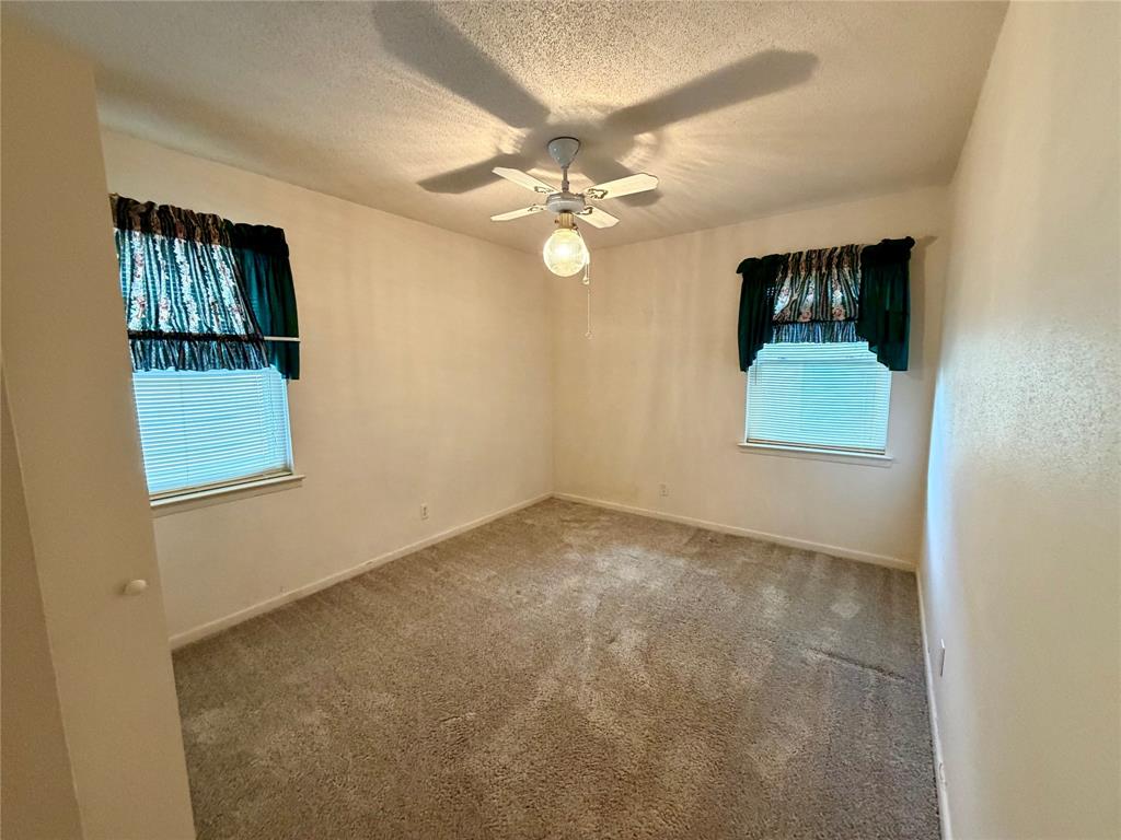 2030 Sycamore Street Paris, TX 75460 - Photo 13 of 24 Carpeted room featuring a ceiling fan with integrated lighting, two windows with blinds, and neutral wall tones