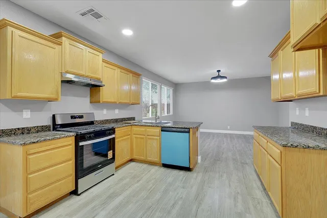a kitchen with granite countertop wooden floors and stainless steel appliances
