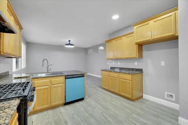 a kitchen with stainless steel appliances granite countertop a sink a stove wooden cabinets and a dining table