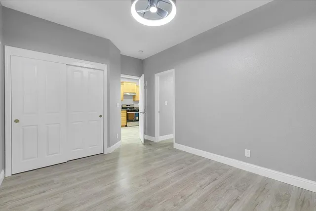 a view of an empty room with wooden floor and closet