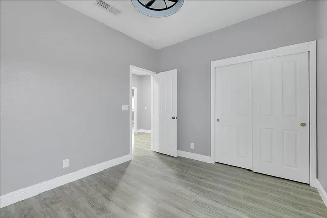 a view of an empty room with wooden floor and window