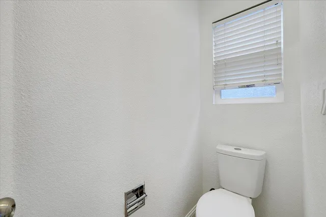 a white toilet sitting next to a white wall