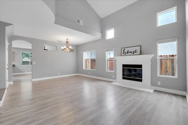 an empty room with wooden floor fireplace and windows