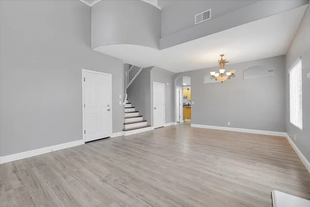 a view of an empty room with wooden floor and a ceiling fan