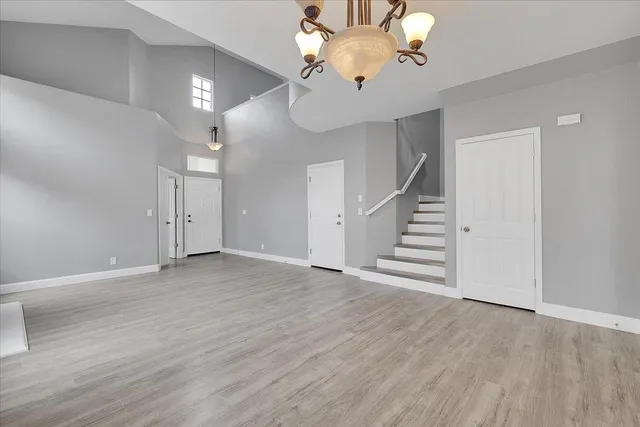 wooden floor in an empty room with a chandelier fan