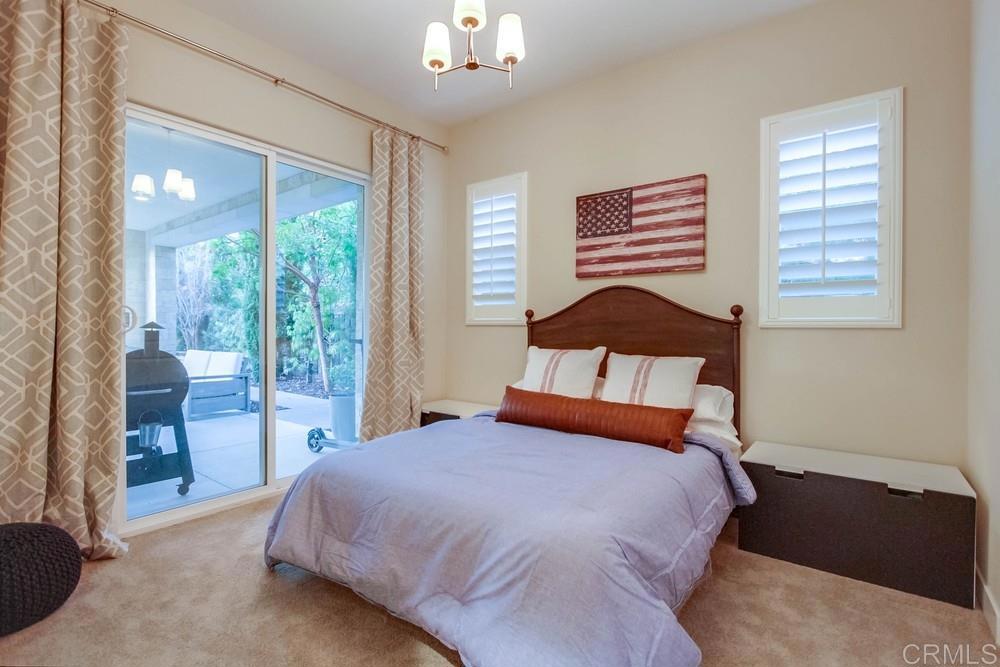 7177 Sitio Corazon Carlsbad, CA 92009 - Photo 23 of 41 a bedroom with a large bed and a chandelier