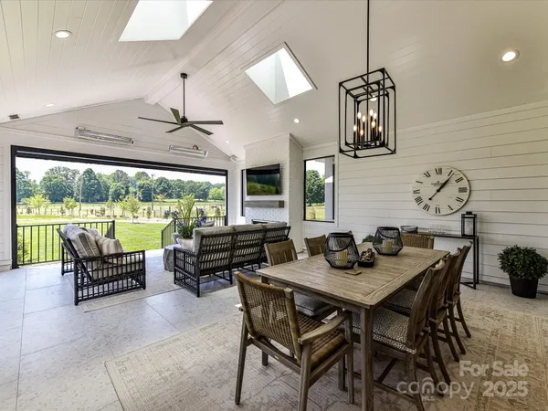 a dining room with furniture a chandelier and large windows