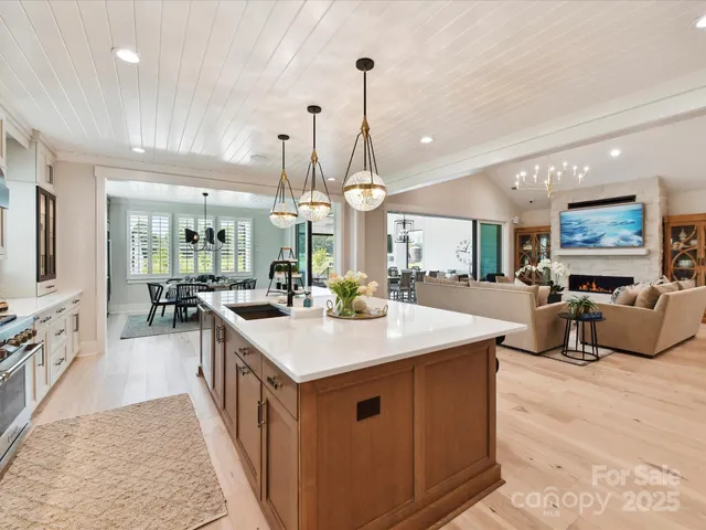 a large kitchen with kitchen island a stove a sink a refrigerator and a view of living room
