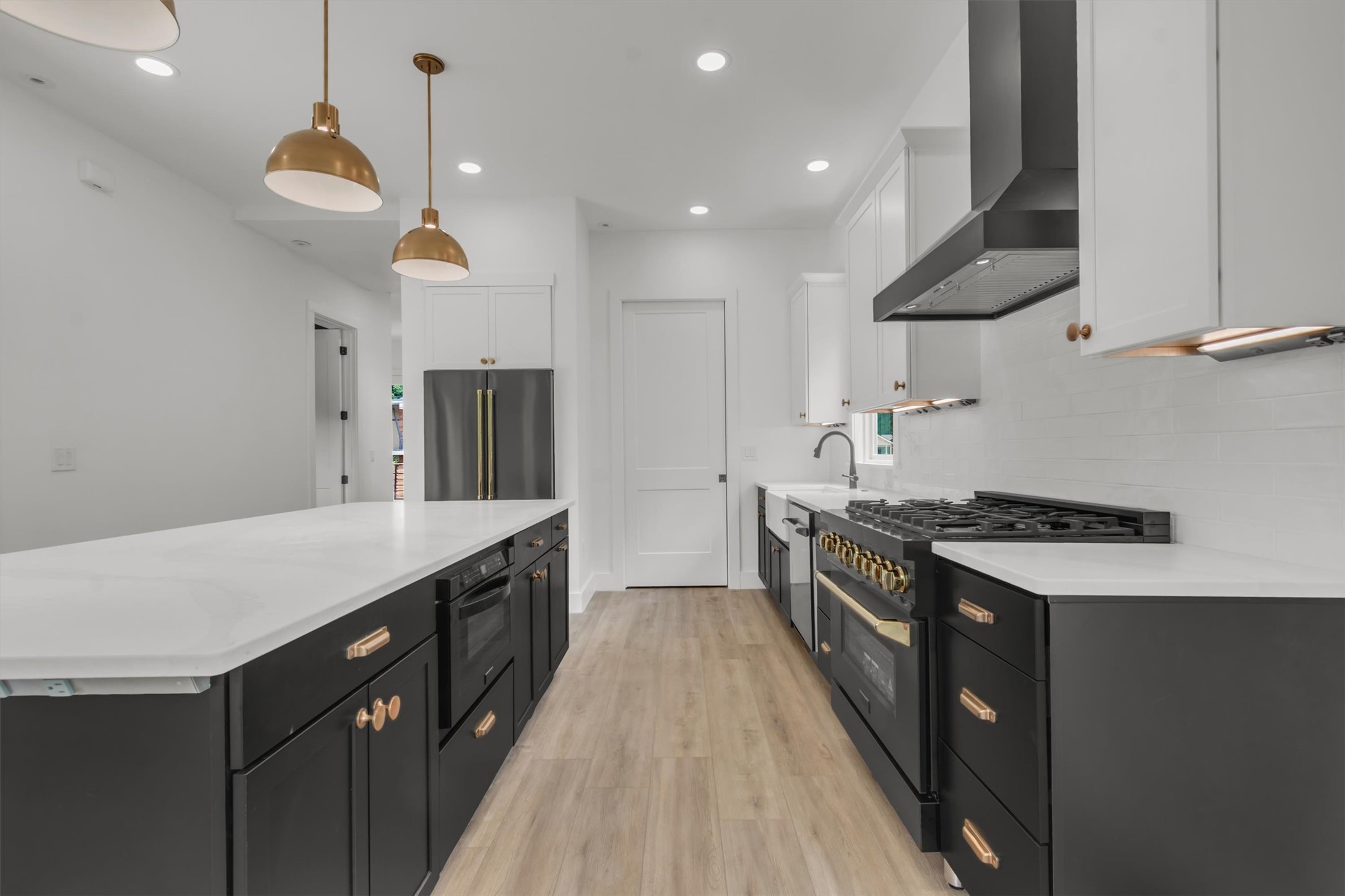 3101 Lyons Road Austin, TX 78702 - Photo 9 of 40 A sleek modern kitchen offers sophisticated black cabinetry, pristine white countertops, and warm brass accents.