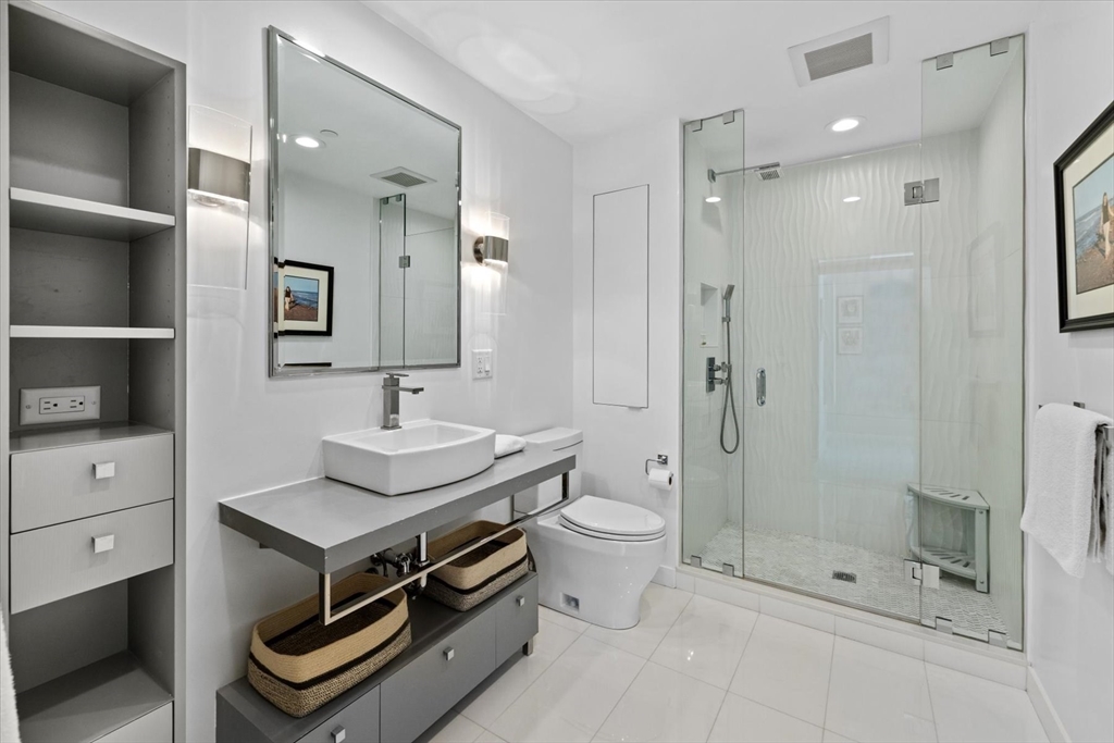 80 Broad Street, Unit 808 Boston, MA 02110 - Photo 18 of 27 a bathroom with a sink a toilet a mirror and shower