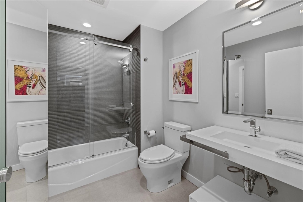 80 Broad Street, Unit 808 Boston, MA 02110 - Photo 22 of 27 a bathroom with a bathtub shower sink mirror and toilet