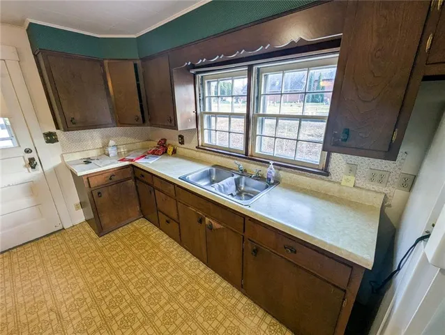 a kitchen with stainless steel appliances granite countertop a stove a refrigerator a sink a dining table and chairs with wooden floor