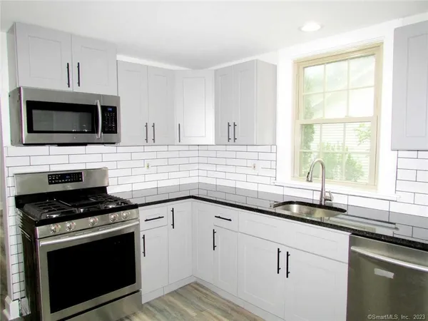 a kitchen with cabinets stainless steel appliances a sink and a window