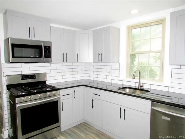 a kitchen with cabinets stainless steel appliances a sink and a window