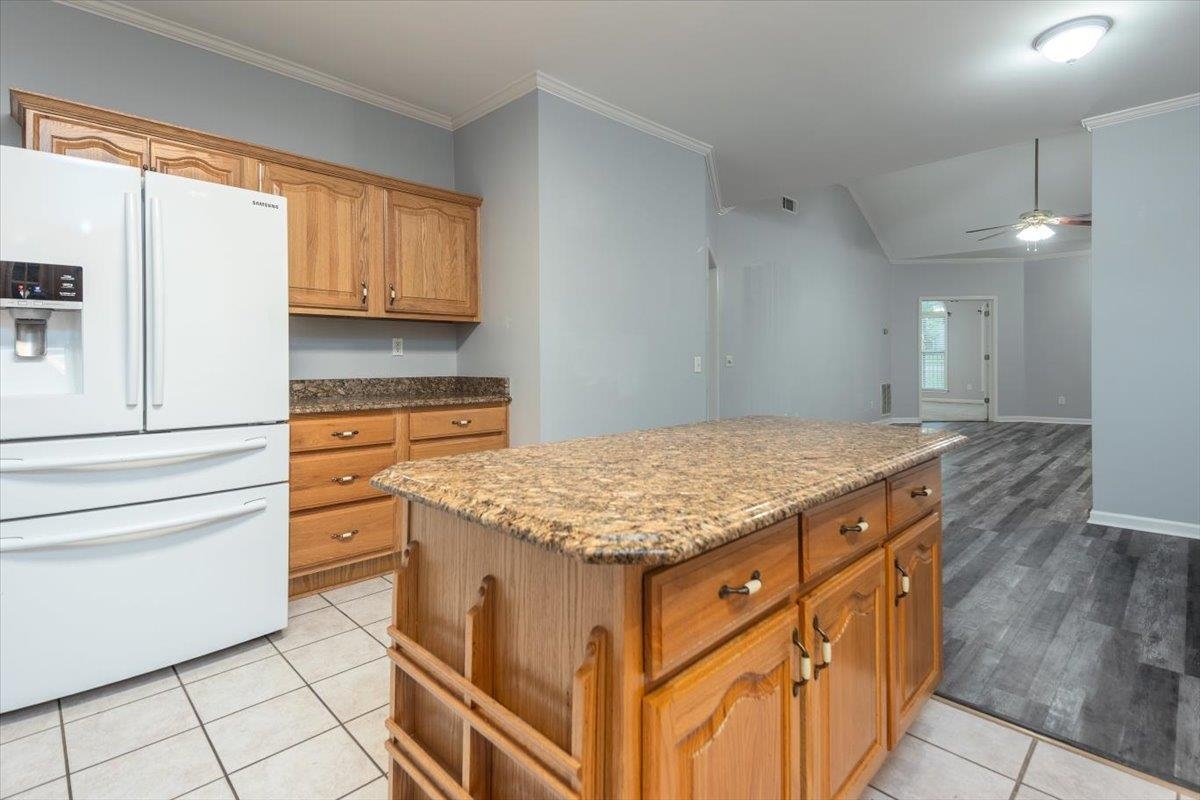 346 Beaver Road Munford, TN 38058 - Photo 11 of 24 Kitchen with a ceiling fan, a center island, brown cabinetry, light stone counters, and white refrigerator with ice dispenser